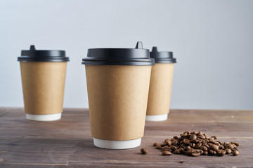 Paper coffee disposable cup for take away or to go, wooden table, space for design mock-up.