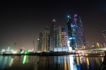 Obraz premium Dubai, United Arab Emirates - October, 2018: Colorful evening on canal and promenade in Dubai Marina, United Arab Emirates