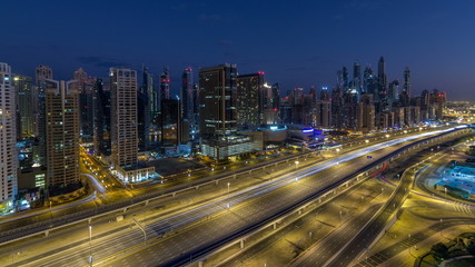 Naklejka na ściany i meble Dubai Marina skyscrapers aerial top view before sunrise from JLT in Dubai night to day timelapse, UAE.