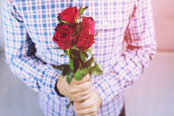 Handsome man plaid shirt hand holding out Bouquet of beautiful with red rose flower. valentine day concept. soft focus.