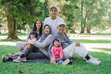 Fototapeta premium portrait of family with parent, grandparent and grandchildren together relaxing in the park