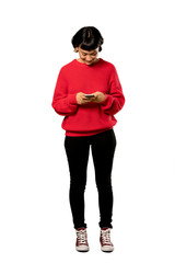 A full-length shot of a Short hair girl with red sweater sending a message with the mobile over isolated white background