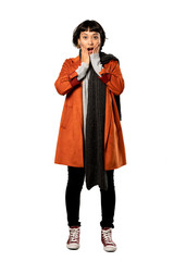 A full-length shot of a Short hair woman with coat surprised and shocked while looking right over isolated white background