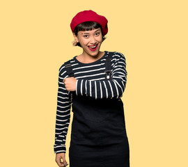 Young woman with beret smiling a lot over yellow background