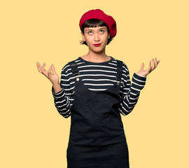 Young woman with beret frustrated by a bad situation over yellow background