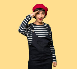 Young woman with beret has just realized something and has intending the solution over yellow background