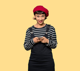 Young woman with beret sending a message with the mobile