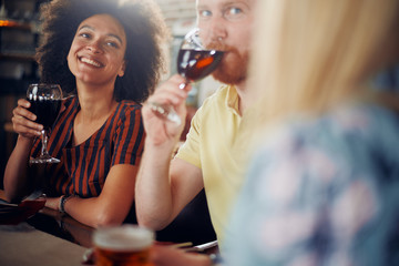 Friends chatting and drinking alcohol while  sitting at restaurant. Multi ethnic group.