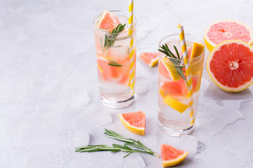 Grapefruit lemonade. Two glasses of refreshing drink, water with  grapefruit, rosemary branches and ice. Recipe concept, cocktail