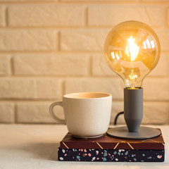 Working notebooks and gliders on the desktop on which there is a lamp and a cup of coffee. Minimalism in the workplace in the interior