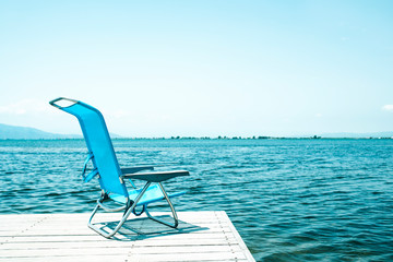blue deck chair on a wooden pier