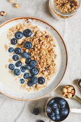 Top view on healthy breakfast, a bowl with organic granola, chocolate pieces, fresh blueberries, hazelnuts and soya milk.