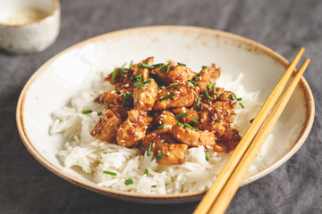 Sesame chicken pieces with rice on a ceramic plate. Chinese traditional dish.