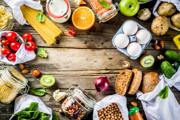 Zero waste shopping and sustanable lifestyle concept, various farm organic vegetables, grains, pasta, eggs and fruits in reusable packaging supermarket bags. copy space top view, banner