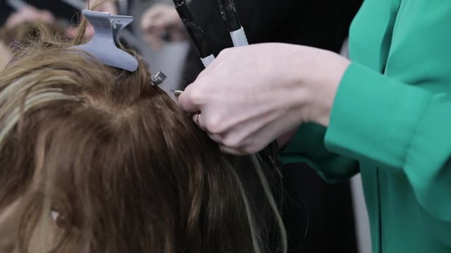 Hairdresser is engaged in artificial hair extensions in the beauty salon. The enlargement process of the hair capsules. Cold tape build-up.