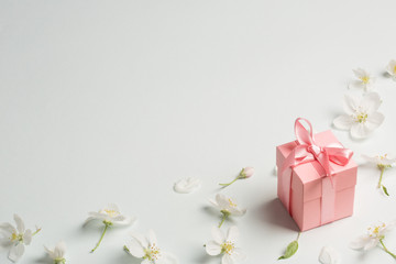 pink gift surrounded by Apple flowers. gentle background, copy space. present for mother's day, spring, Valentine's day, women's day