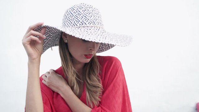 Elegant model posing in red dress and hat on white background