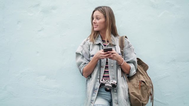 Young backpacker texting outdoors on blue background