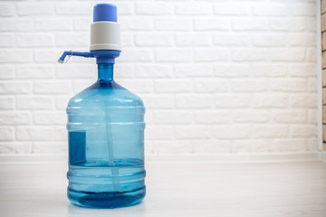 Large bottle of water purified with a pump, against a brick white wall