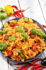farfalle. Delicious creamy Italian penne pasta starter with pepper seasoning and fresh basil viewed from above on rustic
