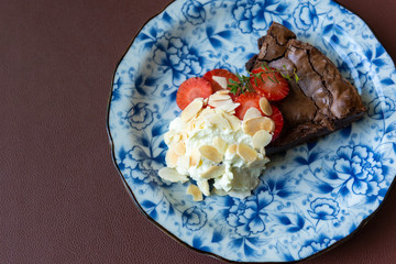 Brownie cake with strawberry in dish on brown background