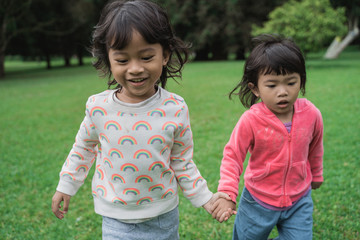 two asian happy young girls running together and holding hand in the park