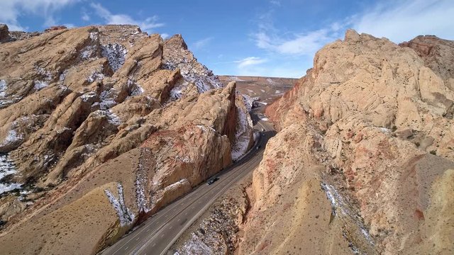 Aerial view of truck convoy driving through gorge on freeway through the San Rafael Swell on I-70 in the Utah desert.