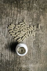 Capsules with herbal medicine on the old wooden table.
