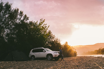 Fototapeta na wymiar woman taking picture of sunrise on her phone. car camping.