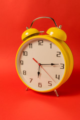 Yellow Retro style alarm clock with fifteen minutes past six o'clock.