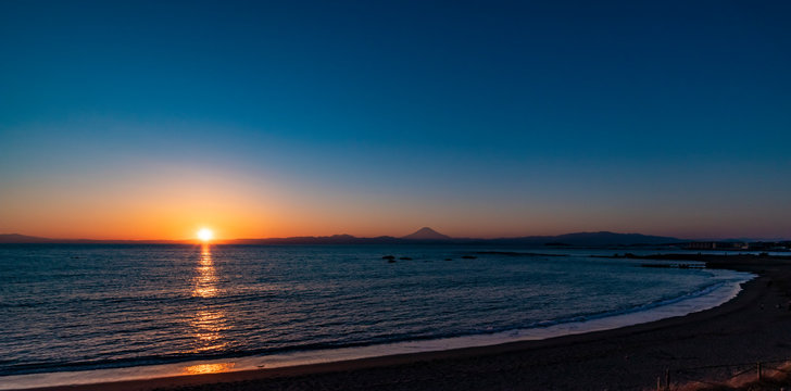 夕焼けの富士山を湘南の海岸越しに撮影
