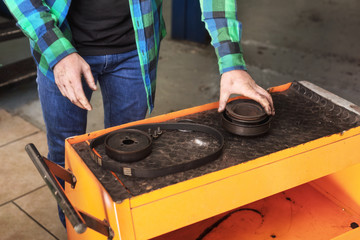 Mechanic picking up a gear from working table .