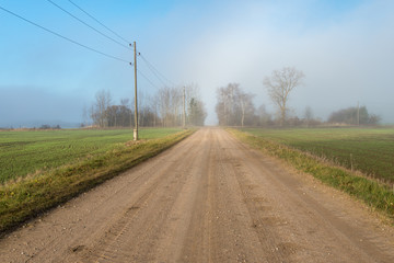 Fototapeta premium empty country gravel road with mud puddles and bumps