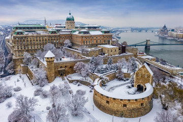 Budapest, Hungary - Aerial view of the snowy Buda Castle Royal Palace from above with the Szechenyi Chain Bridge and Parliament of Hungary at winter time - Powered by Adobe