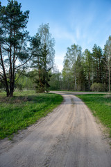 empty country gravel road with mud puddles and bumps