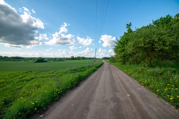 empty country gravel road with mud puddles and bumps