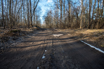 empty country gravel road with mud puddles and bumps