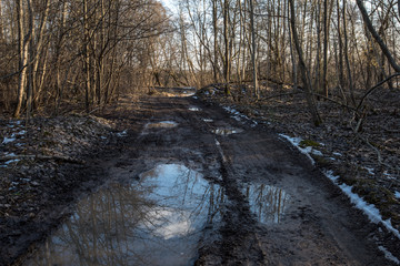empty country gravel road with mud puddles and bumps