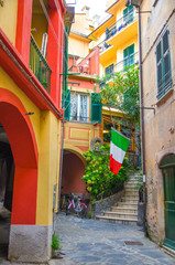 Typical small italian yard with buildings houses, stairs, shutter window and italian flag in Monterosso village, National park Cinque Terre, La Spezia province, Liguria, Italy