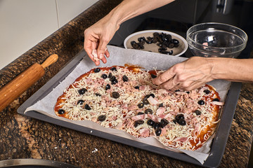 woman hands working on a dough to cook a tasty pizza