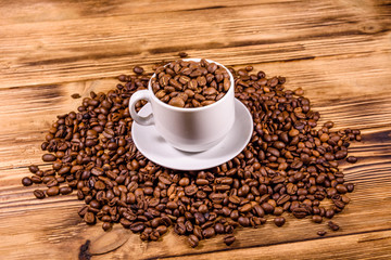 White cup filled with coffee beans on wooden table