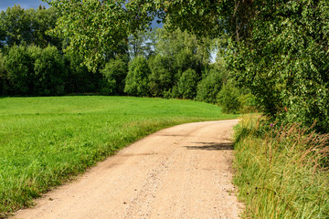 empty country gravel road with mud puddles and bumps