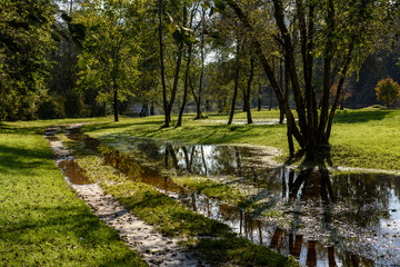 empty country gravel road with mud puddles and bumps