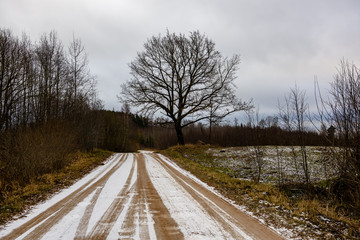 empty country gravel road with mud puddles and bumps