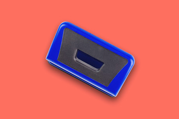 One blue metallic hole puncher in center of office table or school desk living coral color. Top...