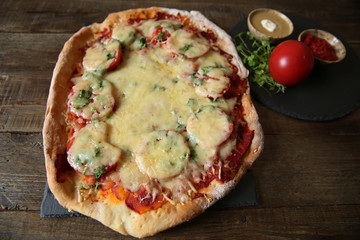 pizza with tomatoes, cheese, herbs and tomato sauce in a bowl on a wooden rustic background