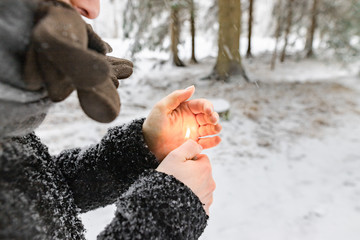 Frau / Mädchen heizt Hände mit Feuerzeug in Kälte zum aufwärmen