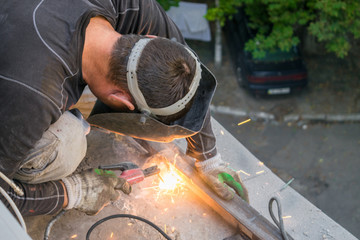 The worker repairs the balcony with a welding machine. View from above. Welding of metal...
