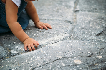 Close up of small baby girl in jeans dress trying to make first steps