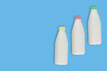 Fresh dairy product in three full plastic bottles for milk, kefir or yoghurt with red and yellow...